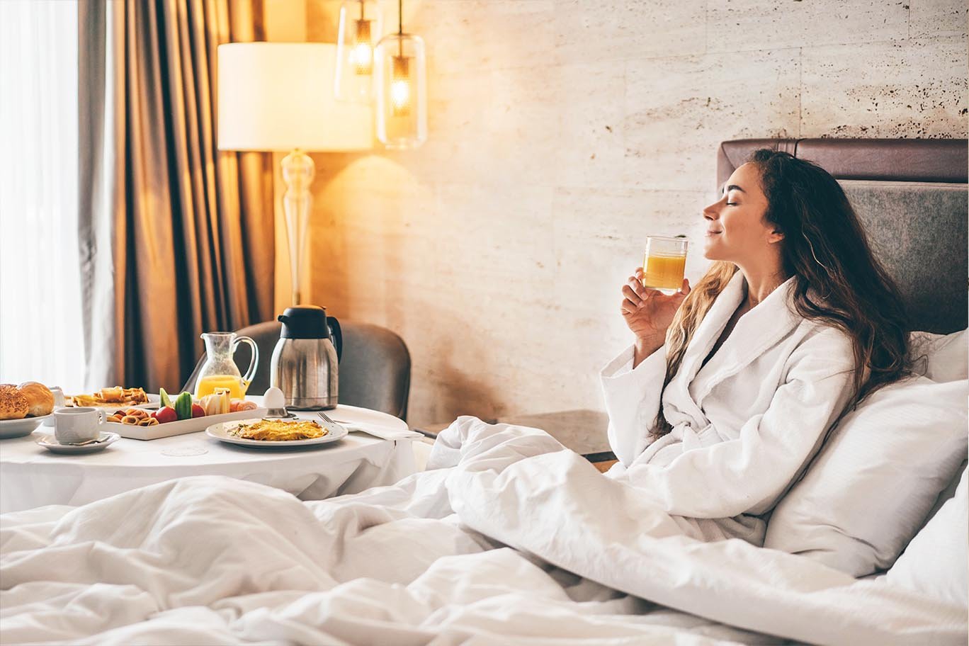 Guest enjoying a luxurious gourmet room service breakfast in bed at Golden Key Hotel.